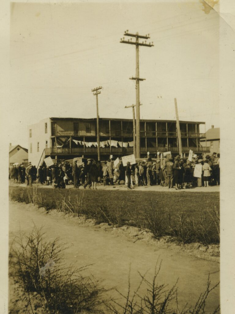 An old photo of a crowd of people in front of a building.